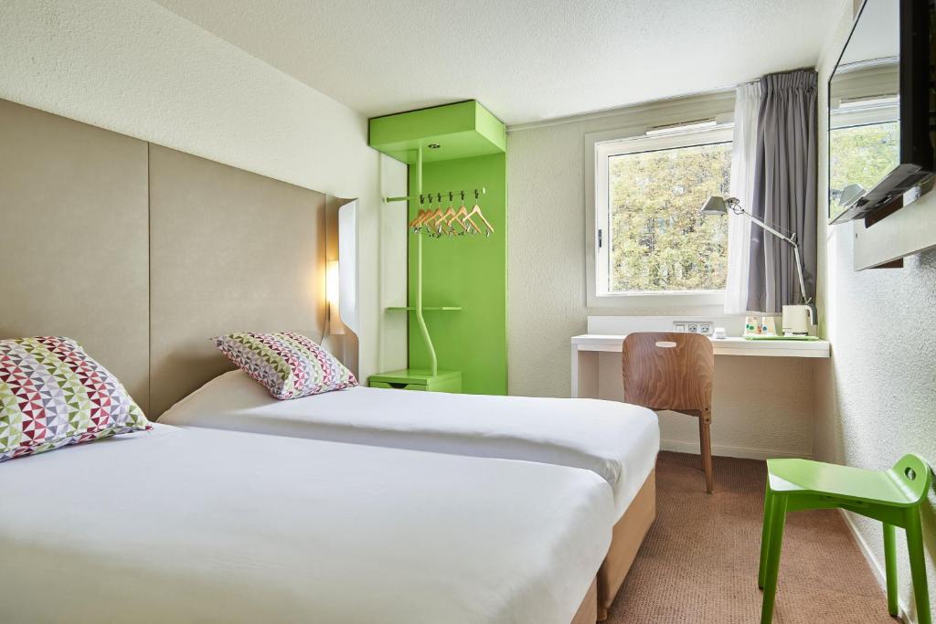 una camera d'albergo con due letti, una scrivania e una finestra di Campanile Paris Sud - Porte d'Orléans - Arcueil ad Arcueil
