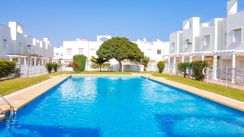 una piscina di fronte ad alcuni edifici bianchi di Garden vistas. Hermoso dúplex con patio, solárium y piscina. a Vera
