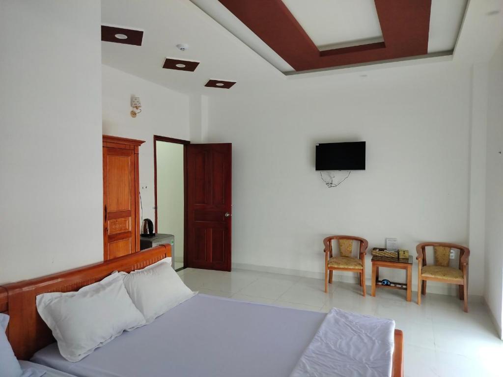 1 dormitorio con 1 cama, TV y mesa en Khách sạn Gia Nghiêm 2, en Ấp Cái Giá