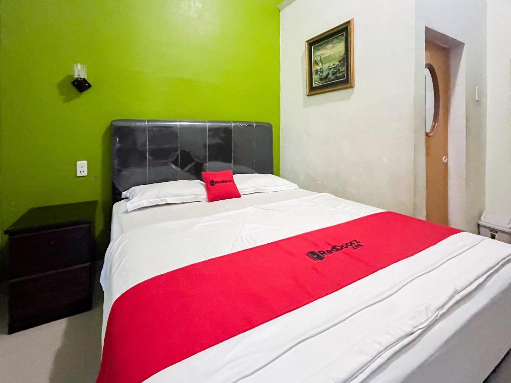 a bed in a room with a red blanket on it at RedDoorz near Pantai Pandan Sibolga 2 in Halangan