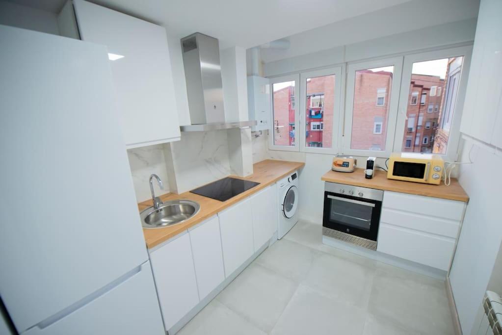 a white kitchen with a sink and a microwave at Apartamento 12 de Octubre, Almendrales in Madrid