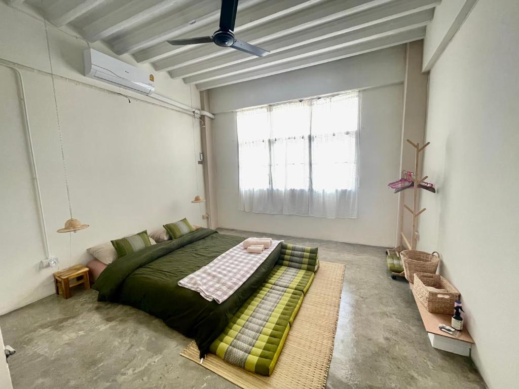 Un dormitorio con una cama verde y una ventana en Baan KhaoSoi - Private room in a rooftop hostel 2nd floor, en Khlong San