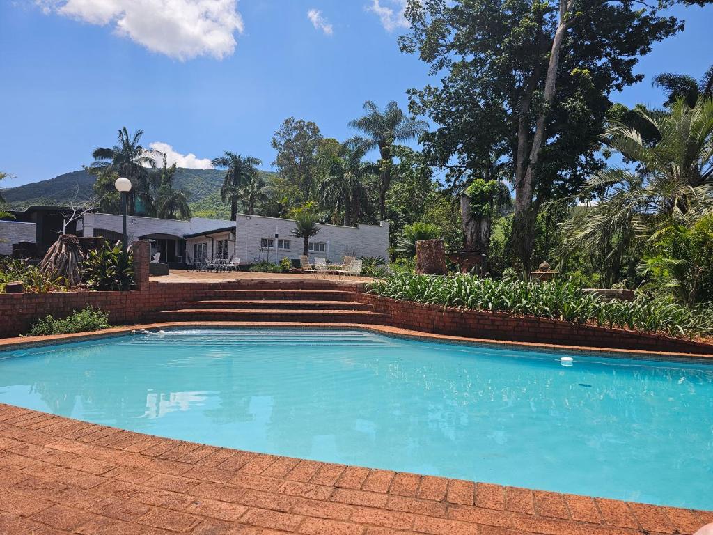 a swimming pool with a brick wall and stairs at Pecan Farm Guesthouse in Louis Trichardt