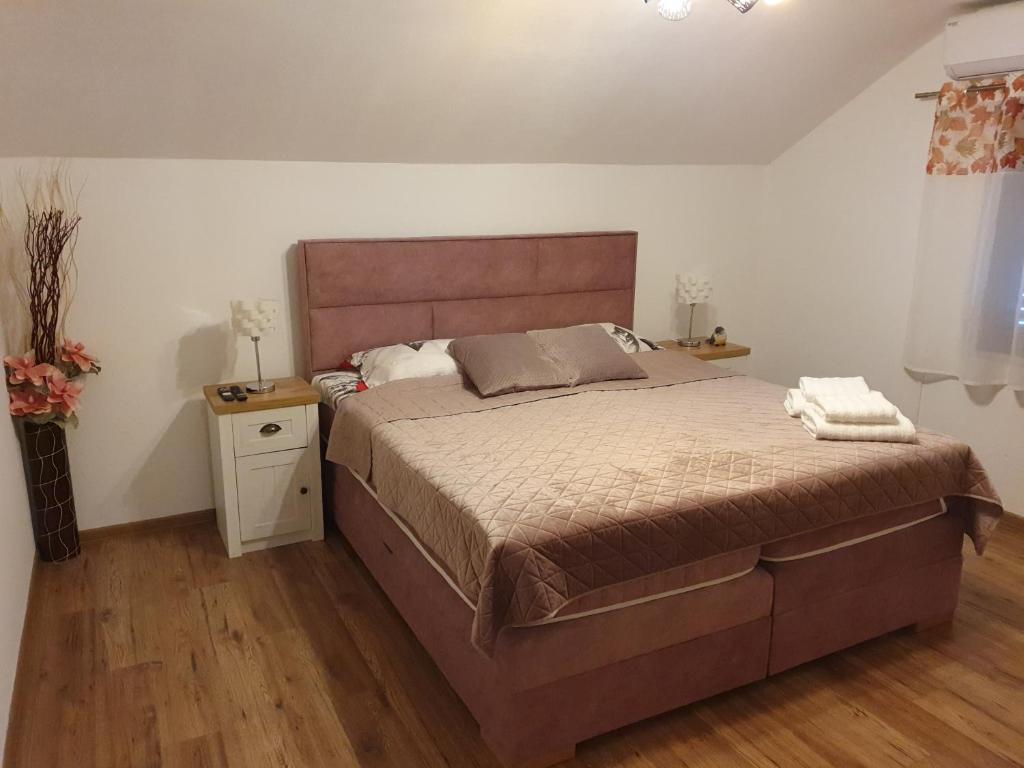 een slaapkamer met een groot bed en een houten vloer bij Apartman Magdalena in Knin