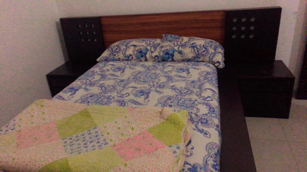 Una cama con edredón y dos mesitas de noche al lado en Rishi Residence Athurugiriya en Athurugiriya