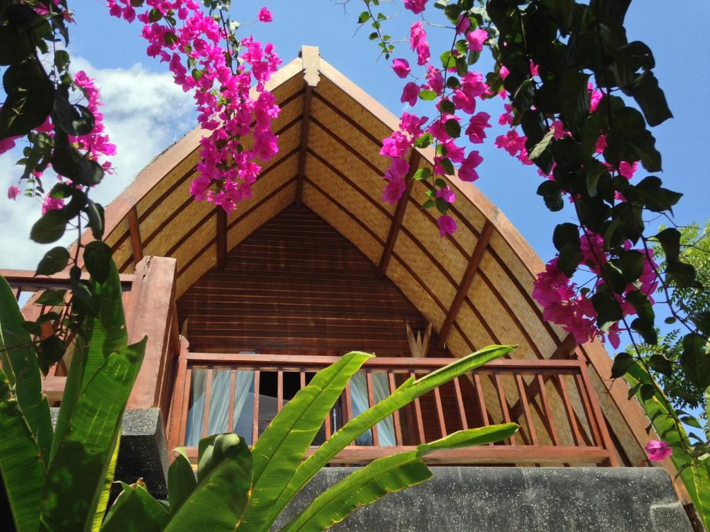 a tree house with pink flowers in the foreground at Rumah Cahaya in Gili Trawangan