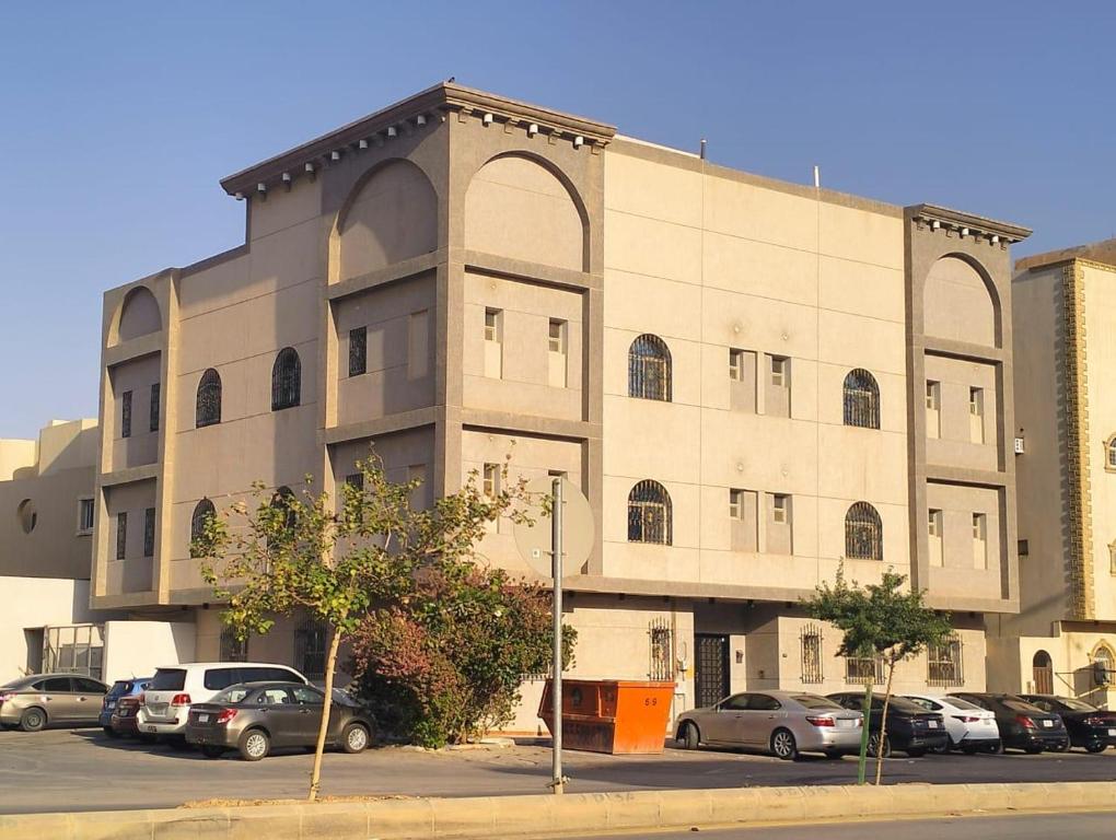 een groot gebouw met auto's geparkeerd op een parkeerplaats bij شقة حي العقيق غمام in Riyad