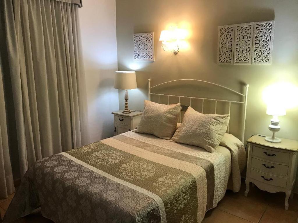 a bedroom with a bed with two night stands and two lamps at Macavi in Rota