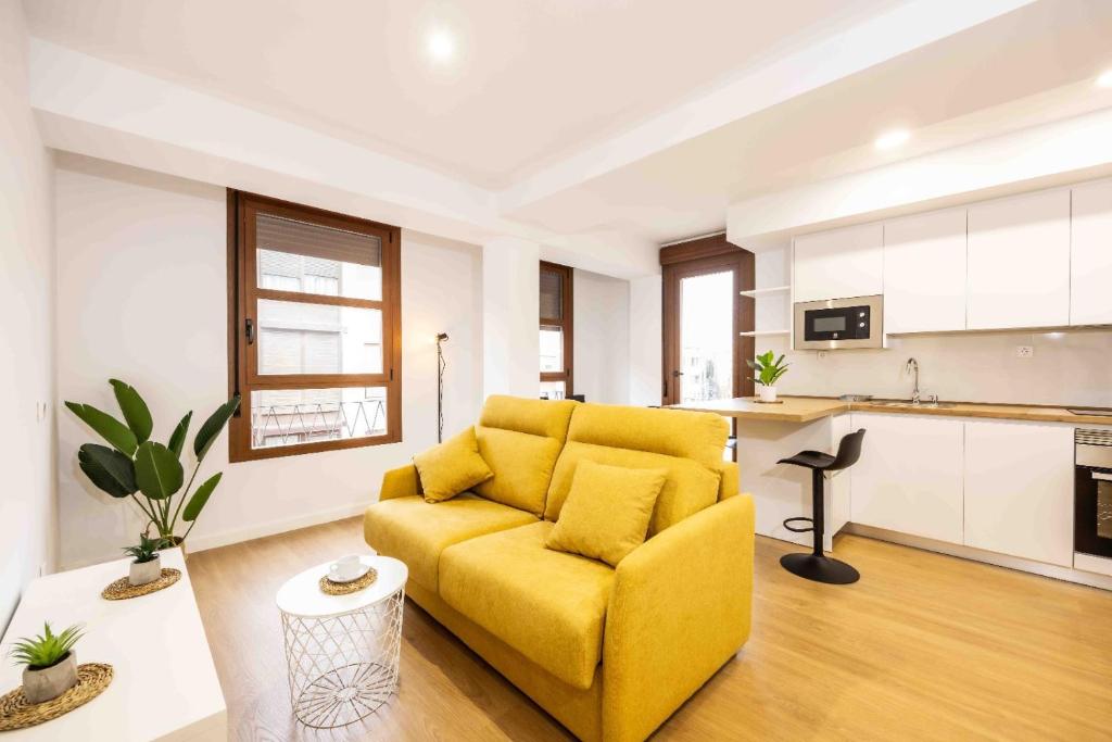 ein Wohnzimmer mit einem gelben Sofa und einer Küche in der Unterkunft Apartamentos turísticos Plaza sevillano , by CartagenaSpain in Cartagena
