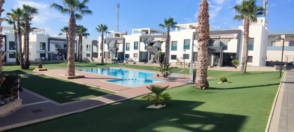 een groot gebouw met palmbomen en een zwembad bij 2 bedroom apartment at Paradise Oasis Beach-ORIHUELA COSTA- LA ZENIA BEACH-ALICANTE in Orihuela-Costa