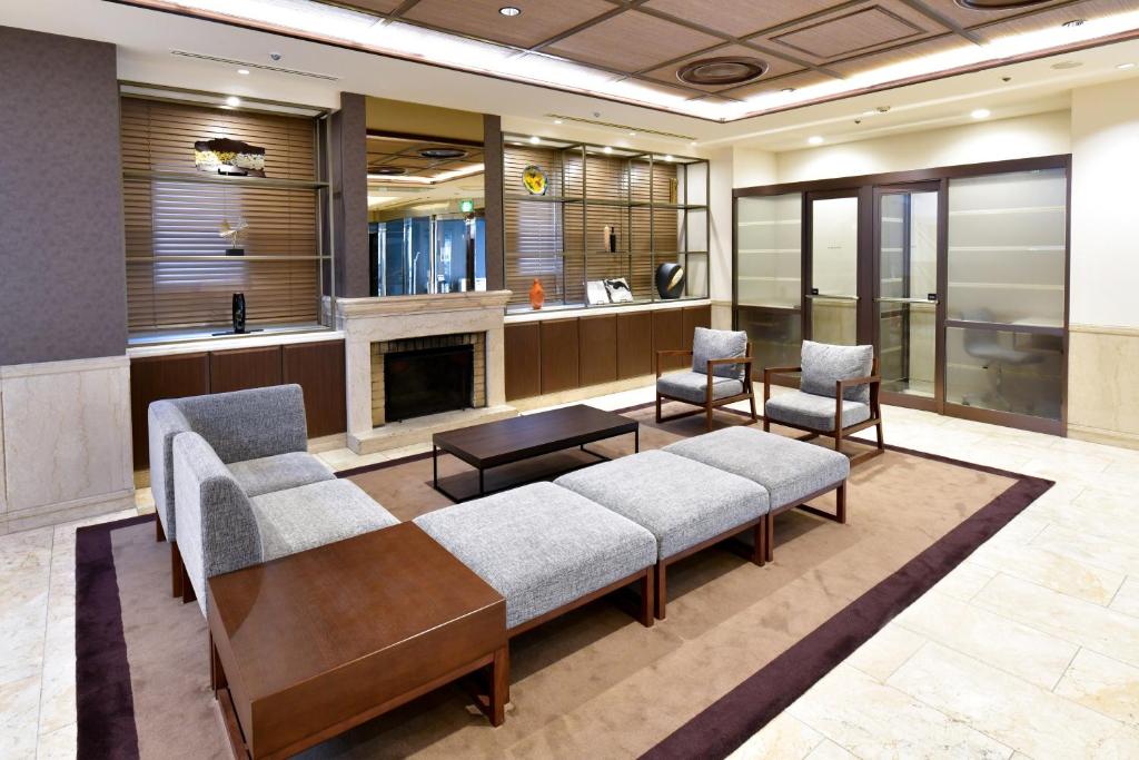 vestíbulo con sofá, sillas y chimenea en HOTEL MYSTAYS Kanazawa Katamachi, en Kanazawa