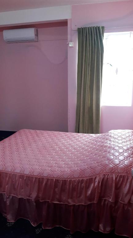 ein Schlafzimmer mit einem Bett mit einer rosa Tagesdecke und einem Fenster in der Unterkunft Karibu in Rivière du Rempart