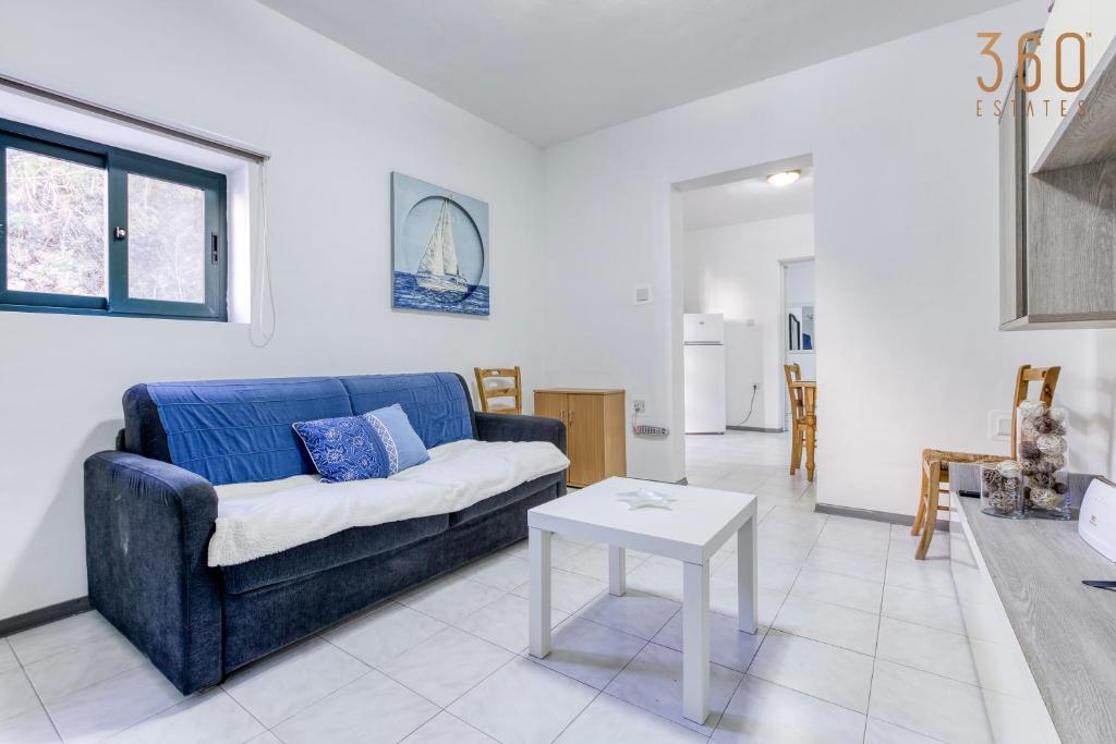 een woonkamer met een blauwe bank en een tafel bij Peaceful 1BR maisonette with Sofa Bed with WIFI by 360 Estates in St Paul's Bay