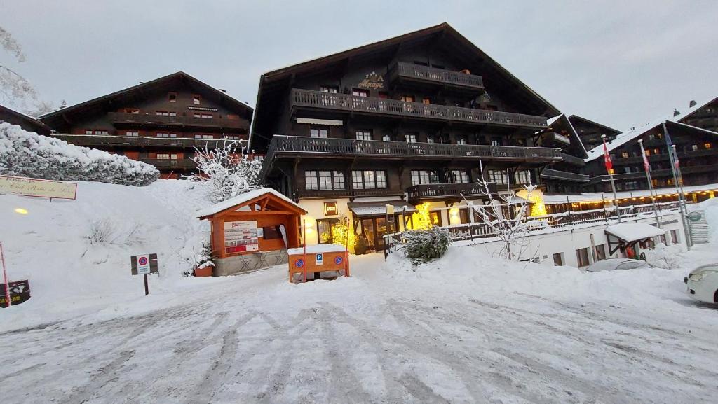 a large building with a snow covered street in front of it at Alpage Immo Location Service in Champoussin