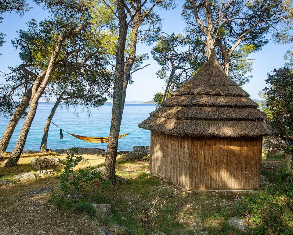 uma cabana junto à água com uma rede em Pine Beach Pakostane - All Inclusive light em Pakoštane