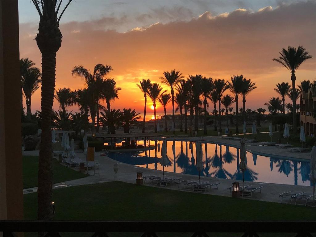 a sunset at a resort with a pool and palm trees at sahl hashesh makadi- hurghada- in Hurghada