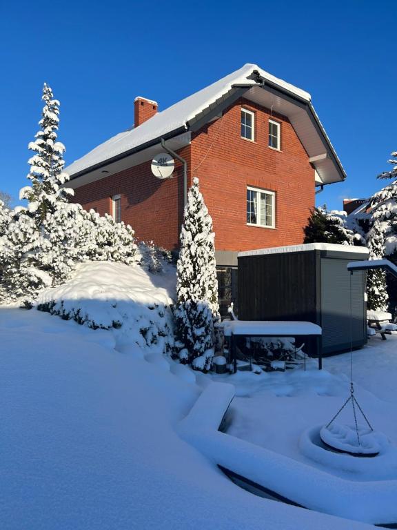 una casa de ladrillo rojo con nieve en el suelo en Domek w Gaiku, en Limanowa
