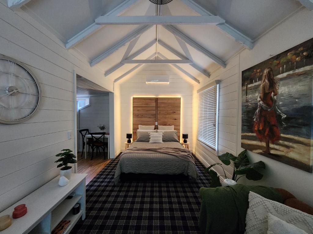 a bedroom with a bed and a clock on the wall at Daylesford - Frog Hollow Estate -THE COTTAGE - enjoy a relaxing and romantic night away in our gorgeous little one Bedroom ROMANTIC COTTAGE under the apple tree with water views in Daylesford