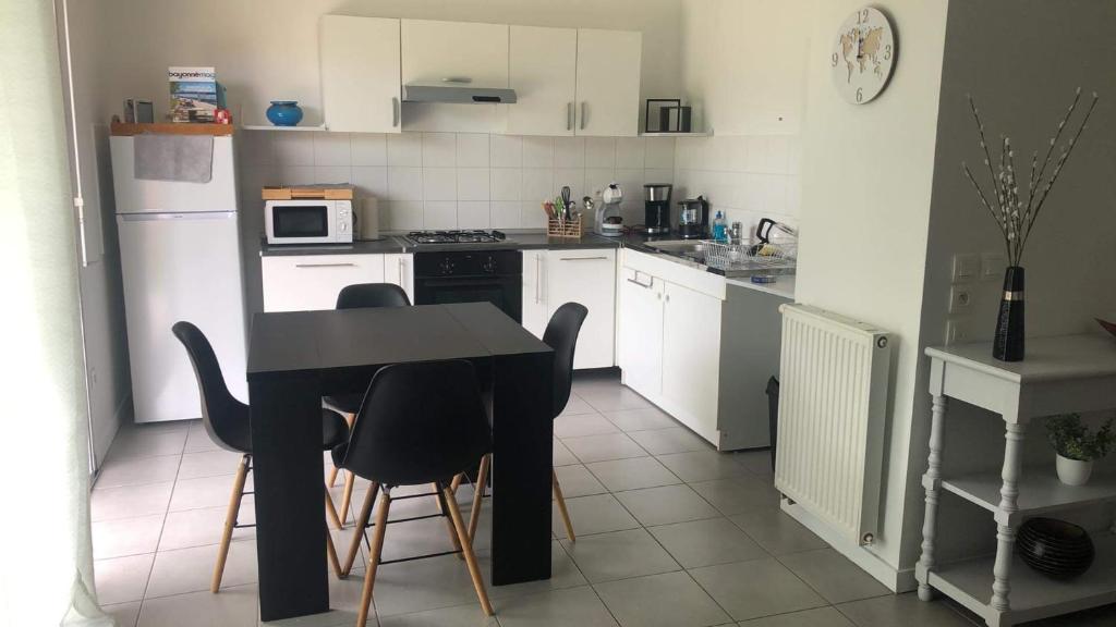 une petite cuisine avec une table et des chaises noires dans l'établissement Appartement T2 Bayonne avec parking, à Bayonne