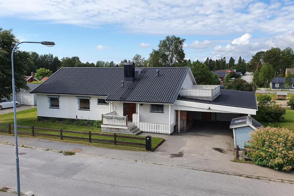 a white house with a black roof and a driveway at Mysigt hus med 9 sovrum nära natur och SCA & Hamn in Holmsund