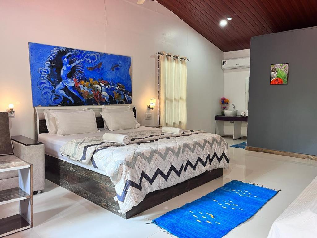 a bedroom with a large bed with a painting on the wall at LOTUS RIYA Homestay in Hampi