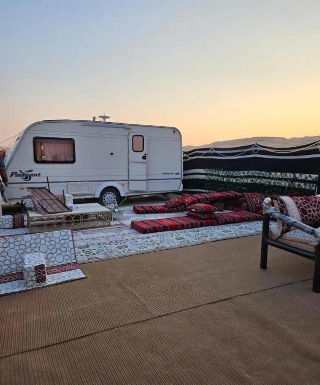 une remorque blanche garée à côté d'une tente avec des oreillers rouges dans l'établissement Al khateem Motor Home, à Liwa