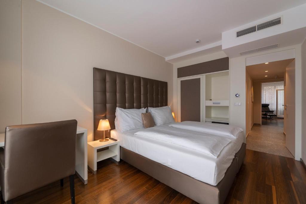 a bedroom with a large white bed and a chair at Pakat Residences in Vienna