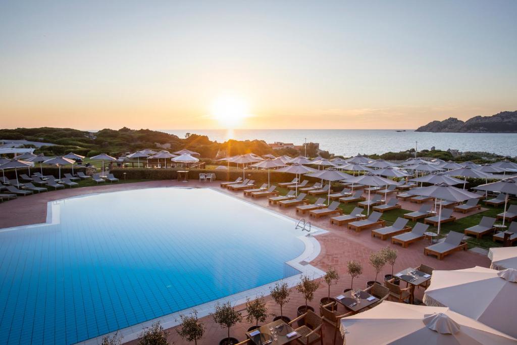 an aerial view of a resort with a pool and umbrellas at Mangia's Santa Teresa Sardinia, Curio Collection by Hilton in Santa Teresa Gallura