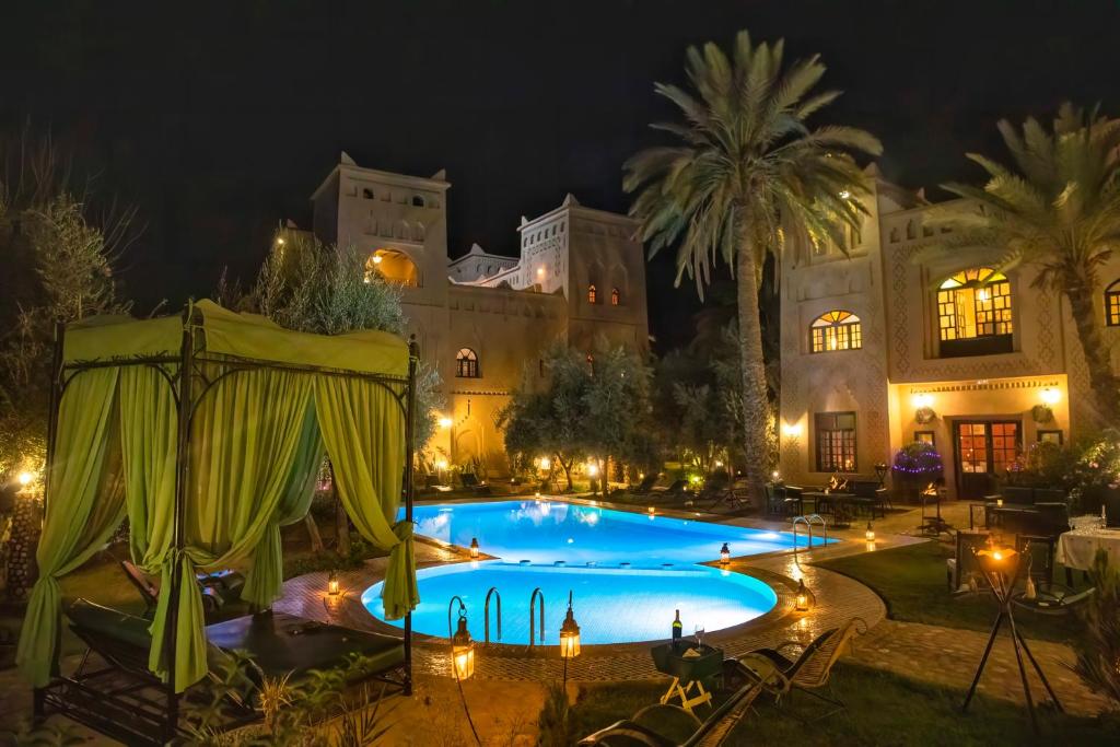 a large building with a swimming pool at night at Ksar Elkabbaba Kasbah & SPA in Skoura