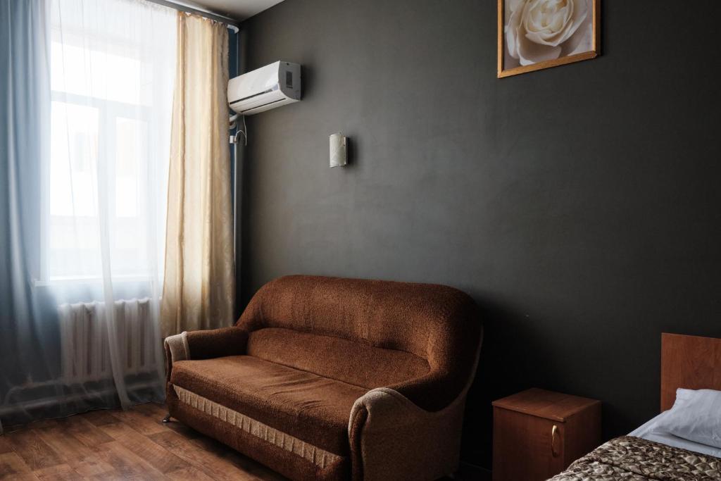 a brown chair in a room with a window at Hotel Europa in Semey