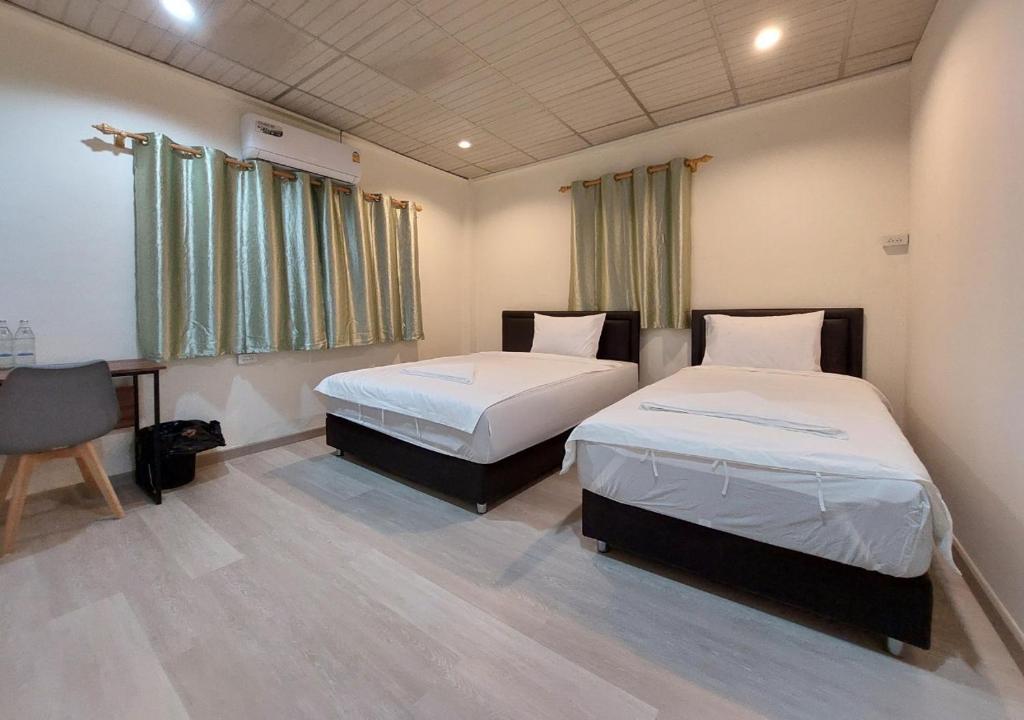 a bedroom with two beds and a table and a chair at Chaiwat Hostel in Bangkok