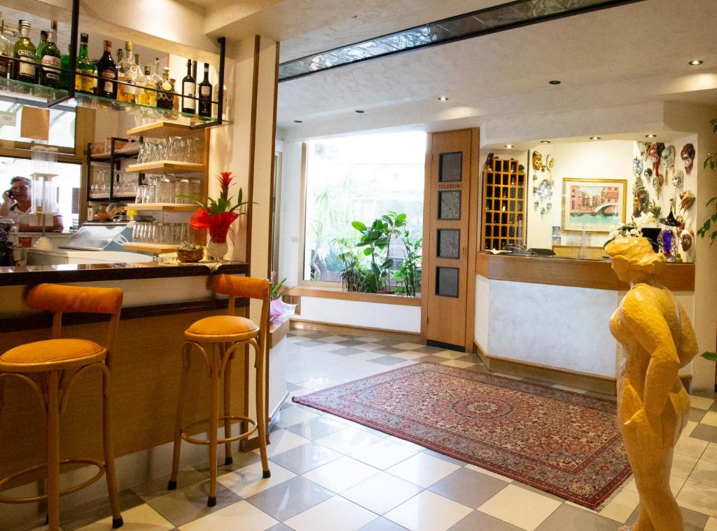 a restaurant with a bar with orange stools at Hotel Berna in Eraclea Mare