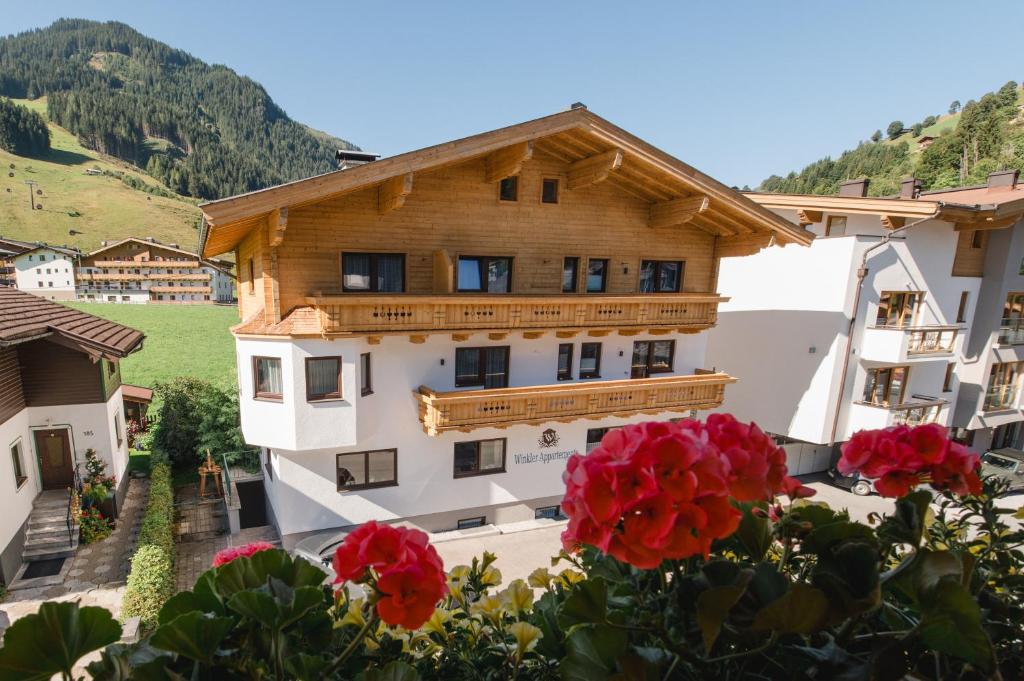 a building with red flowers in front of it at Winkler Appartements in Saalbach-Hinterglemm