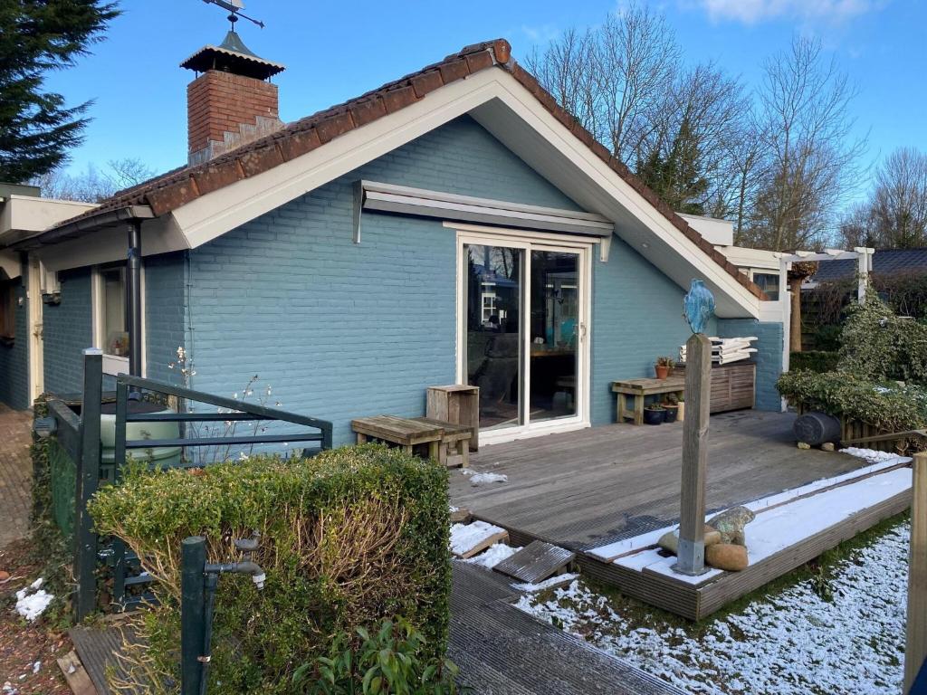 een klein blauw huis met een houten terras bij Amazing holiday home in Lauwersoog with sauna in Lauwersoog