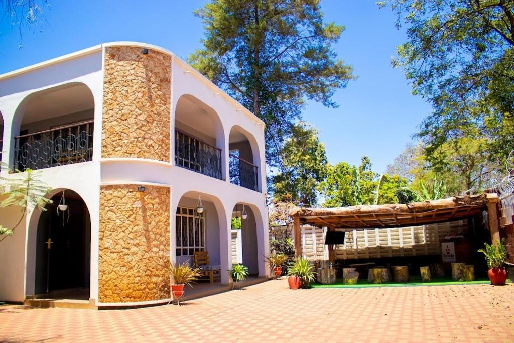 ein großes weißes Gebäude mit einer Veranda und einem Baum in der Unterkunft Asante Home in Arusha