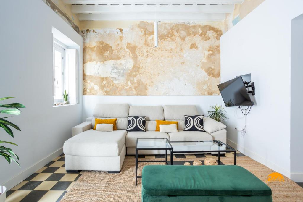 ein Wohnzimmer mit einem Sofa und einem TV in der Unterkunft La Casa del Alfarero by Cadiz Time in Cádiz