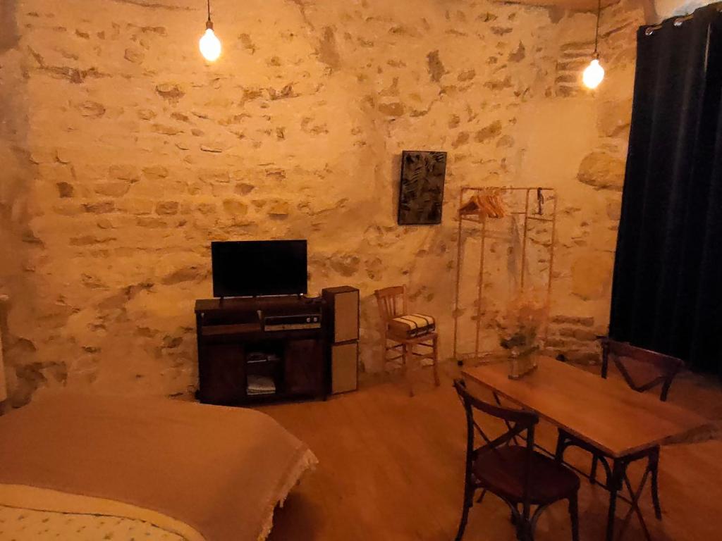 uma sala de estar com uma mesa e uma televisão em Chamade en Beaujolais em Anse