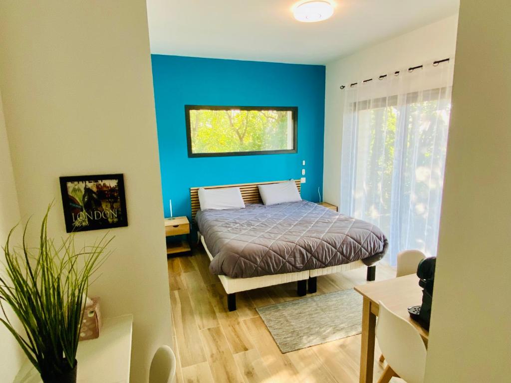 1 dormitorio con cama y pared azul en Deux suites proche MEETT & aéroport, en Aussonne