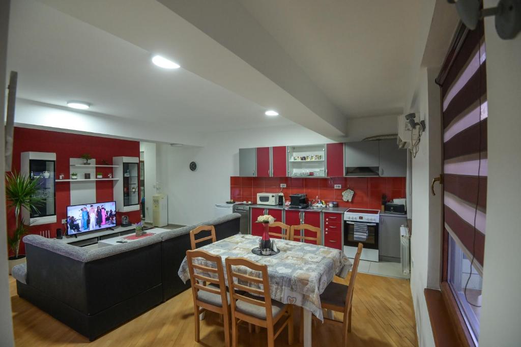 una cocina con armarios rojos y una mesa con sillas. en Elena Apartments - City Center Oasis Modern Elegance in Skopje, en Skopje
