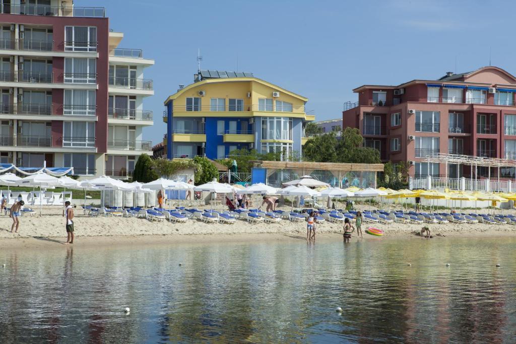 a beach with chairs and umbrellas and people on the beach at Hotel Sofia Beach in Nesebar
