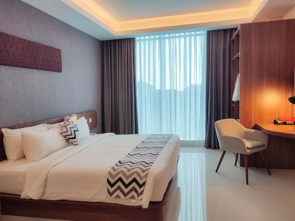 um quarto com uma cama, uma secretária e uma cadeira em UNHAS HOTEL & CONVENTION em Patjinongong