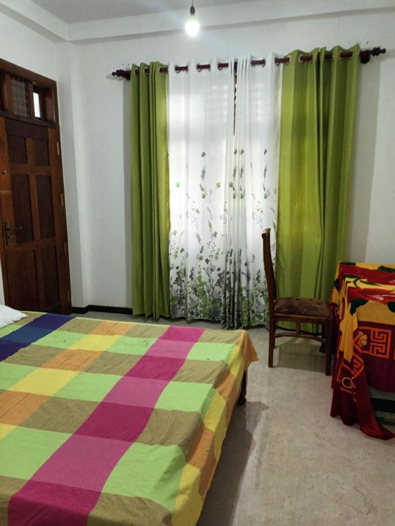 a bedroom with a colorful bed and green curtains at white's vila in Matara