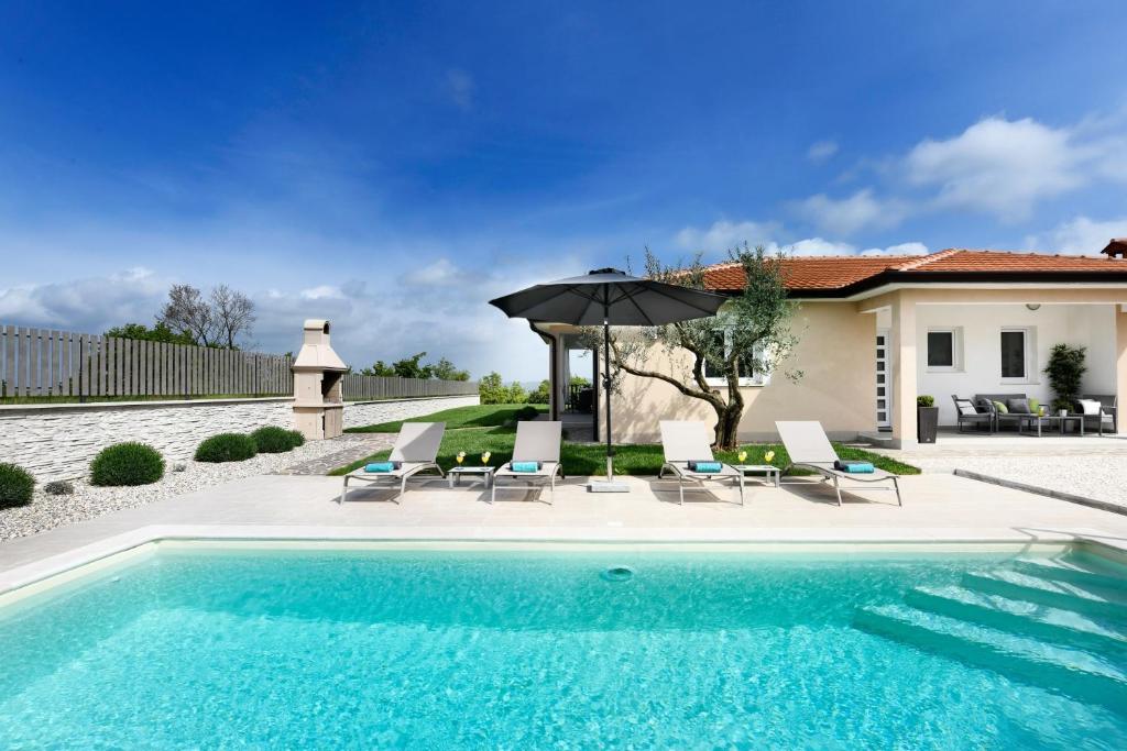 una piscina con sillas y una sombrilla junto a una casa en Villa Olea by Istrabook, en Vižinada