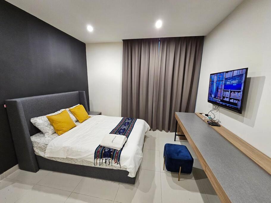 een slaapkamer met een bed en een bureau met een televisie bij Kozi Square comfort Studio Home 3E in Kuching