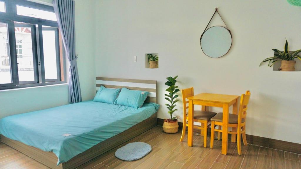 Schlafzimmer mit einem Bett, einem Tisch und einem Spiegel in der Unterkunft Leo's Homestay Phan Rang in Phan Rang