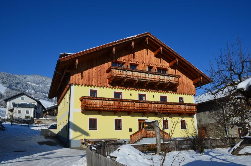 a large building with a wooden roof in the snow at Gästezimmer Peterbauer in Dorfgastein