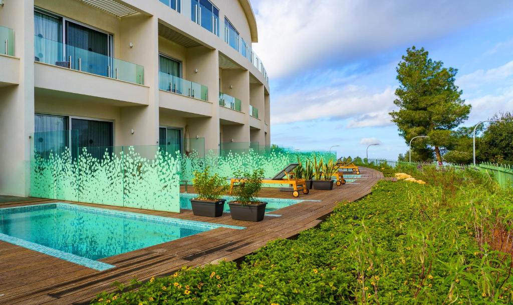 a hotel with a swimming pool and plants next to a building at Almond Hotel - Adults only in Neve Ilan