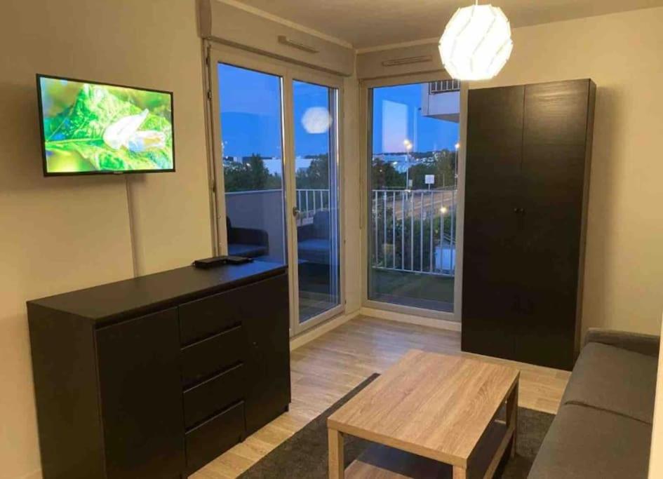 un salon avec une télévision, un canapé et une table dans l'établissement Redelpha, à Carrières-sous-Poissy