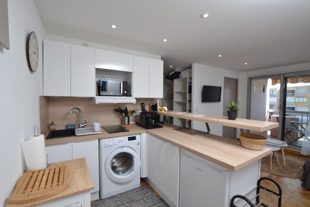 une cuisine avec des armoires blanches et une machine à laver dans l'établissement L'écrin au coeur de la citadelle, au Grau-du-Roi