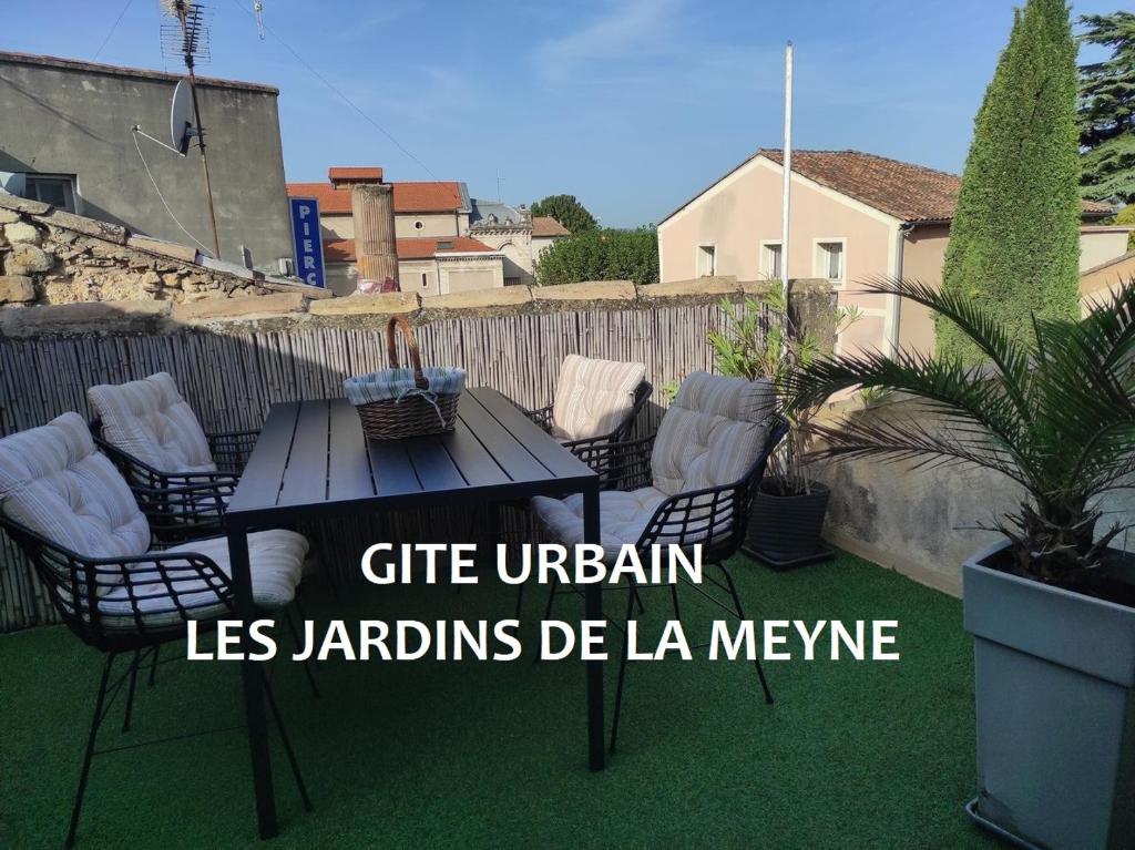 um pátio com uma mesa e cadeiras na relva em Gîte urbain les jardins de la meyne em Orange